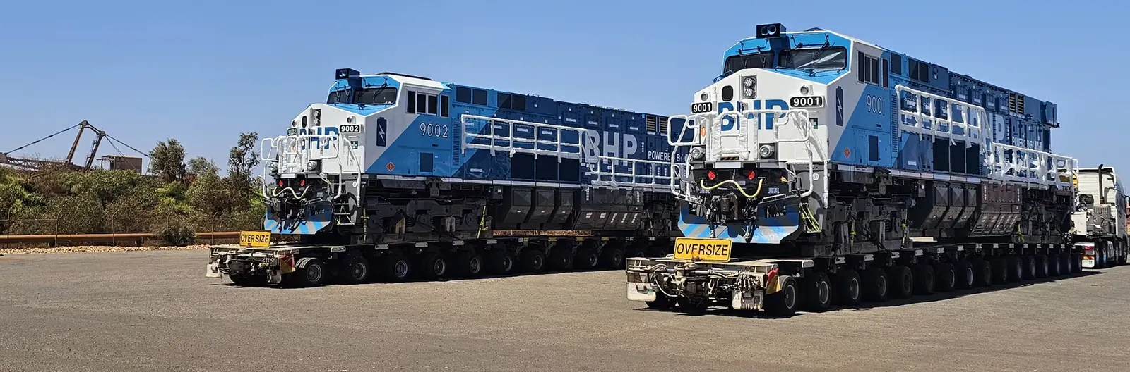 BHP’s two purpose-built battery-electric locomotives, units 9001 and 9002, on road transporters after arriving at Port Hedland in November 2025. Photo: BHP