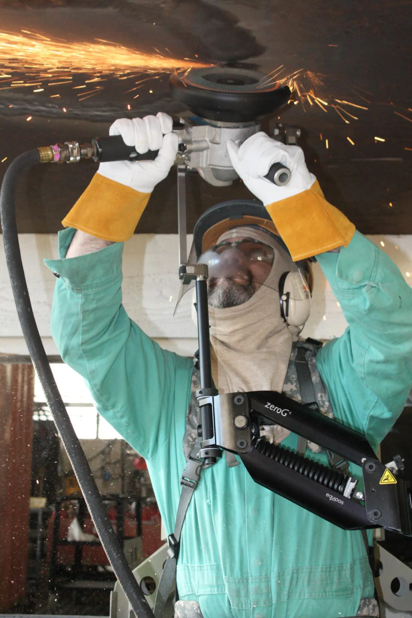 Shipyard worker grinding with an exoskeleton — U.S. Navy photo by Alan Baribeau (public domain)