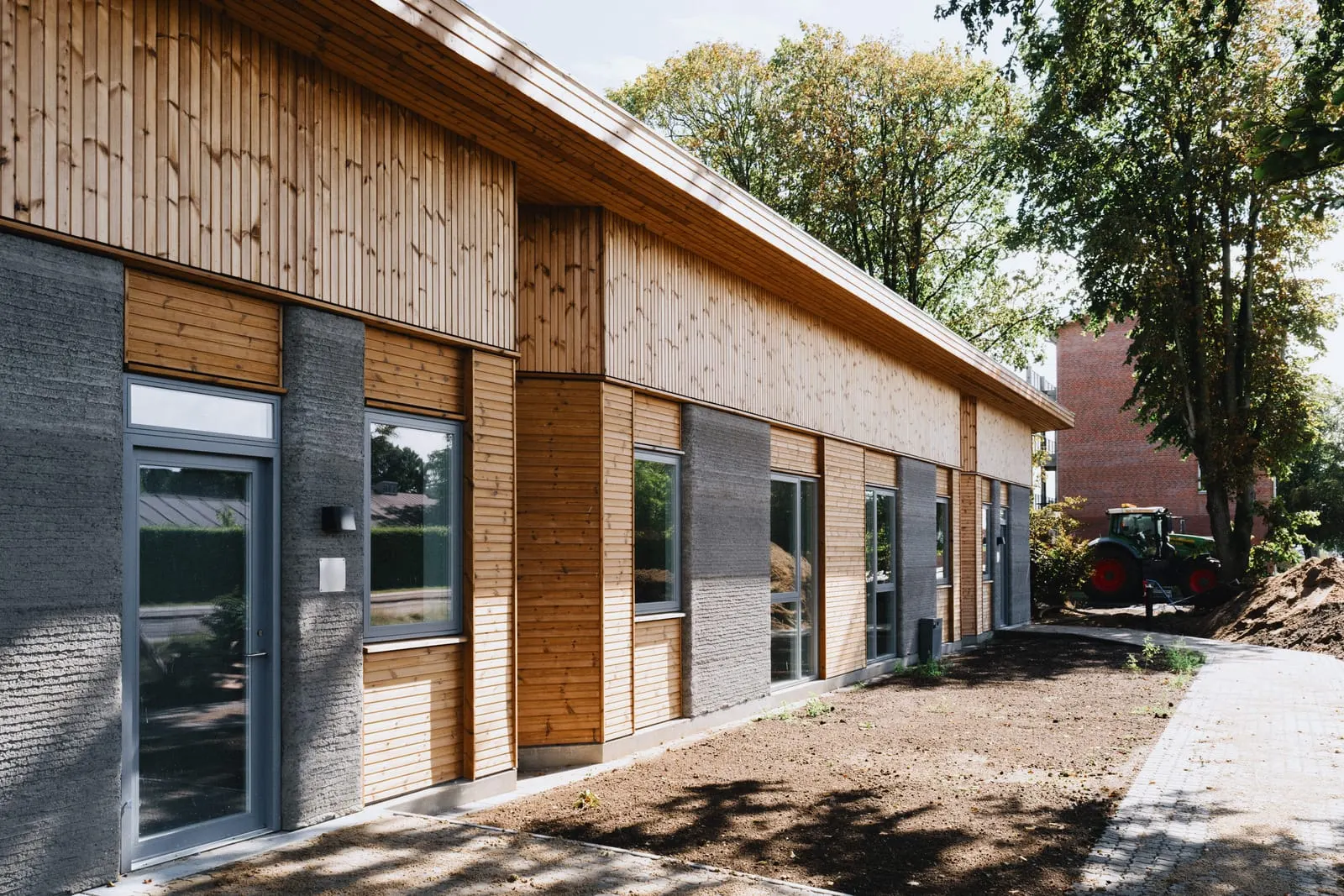 Completed apartments at Skovsporet, Holstebro — printed concrete walls with timber infill and cladding, landscaping still in progress. Photo: Edi Cliff, via the SAGA Space Architects press kit